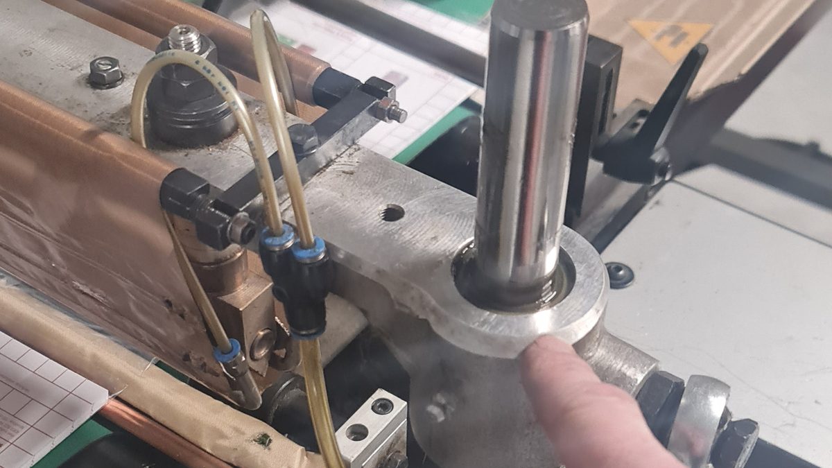 Hand aan een stalen as tijdens werk aan een verpakkingslijn