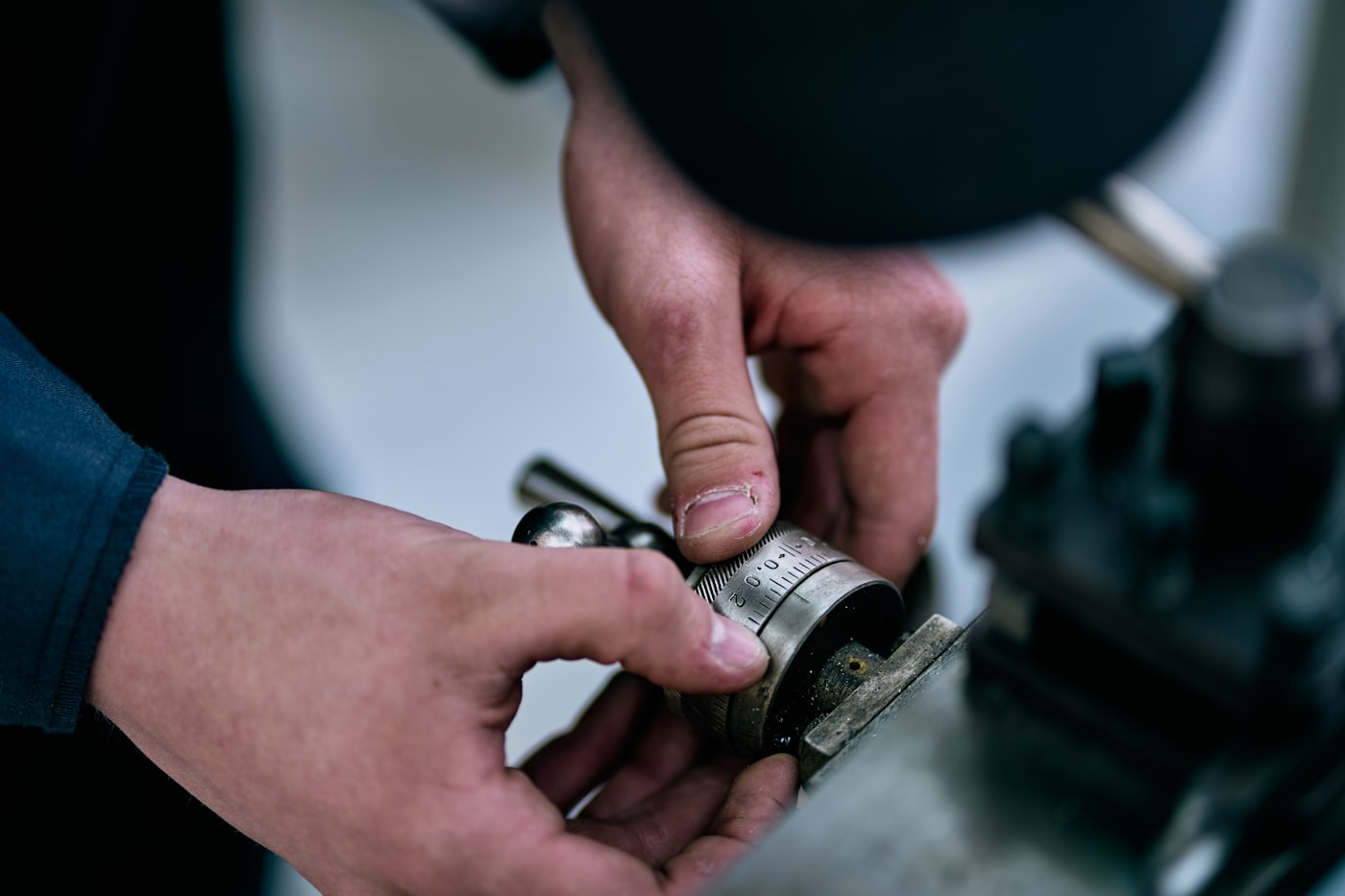 Handen die een metalen onderdeel op een werkbank bewerken