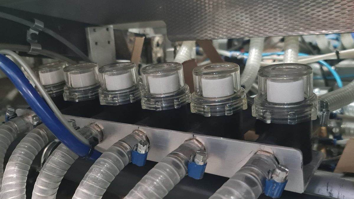 Rij pneumatische cilinders met blauwe luchtleidingen in een verpakkingslijn